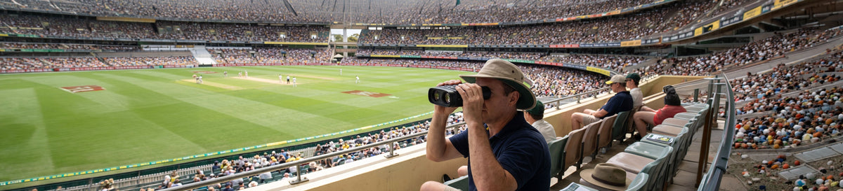 Spectator using HD digital binoculars at a cricket stadium