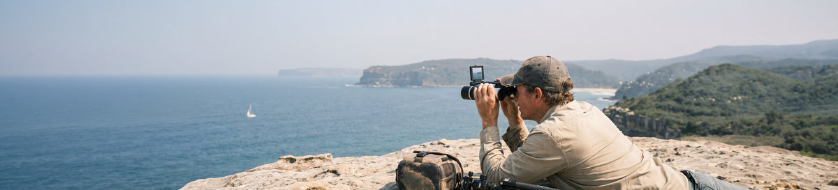 Man using camera binoculars with a built-in screen on a coastal clifftop