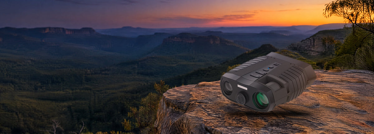 HD digital night vision binoculars resting on a sandstone ledge above a bush valley at dusk